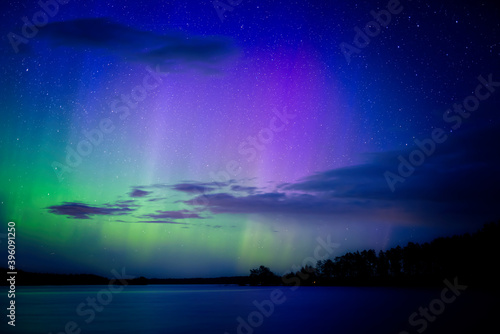 Northern lights dancing over calm lake in Farnebofjarden national park in north of Sweden.