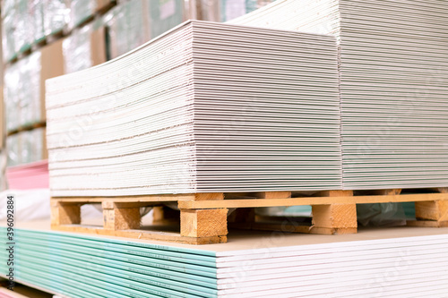 Pallet with Drywall sheets plasterboard in the building warehouse store. Stacking of white gypsum panels, drywall or plasterboard. Gypsum plasterboard in the pack