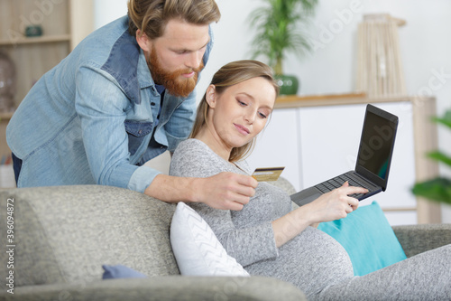 couple enjoying online shopping sitting on sofa at home