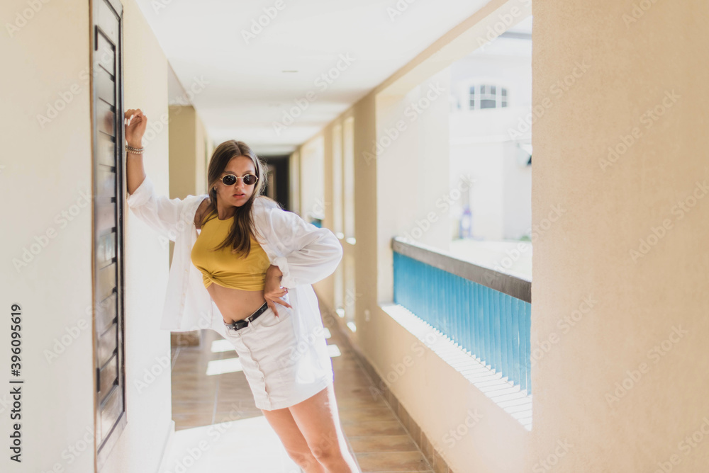 Portrait of beautiful smiling cute tenage model dressed in summer hipster vintage white stylish clothes. Trendy girl posing in the inside background. Funny and positive woman in sunglasses Portrait of beautiful smiling cute tenage model dressed in summer hipster vintage white stylish clothes. Trendy girl posing in the inside background. Funny and positive woman in sunglasses