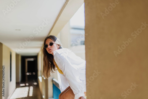 Portrait of beautiful smiling cute tenage model dressed in summer hipster vintage white stylish clothes. Trendy girl posing in the inside background. Funny and positive woman in sunglasses photo