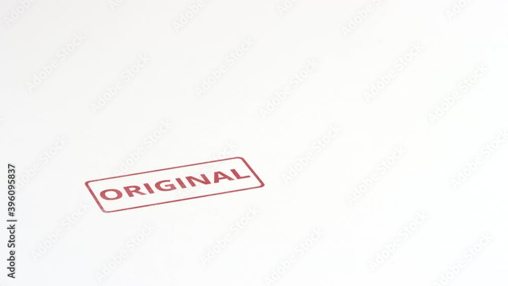 Putting red ORIGINAL rubber stamp on the paper, close-up shot Putting red ORIGINAL rubber stamp on the paper, close-up shot