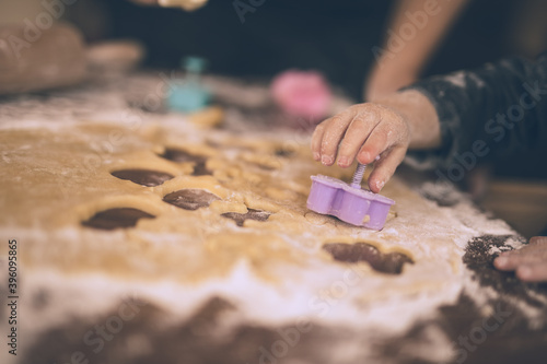 Young child cuts out cookies.