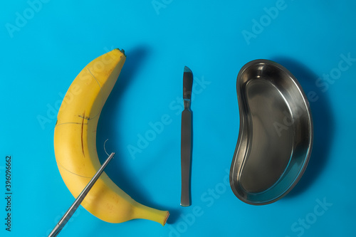 Surgical instruments with a medical Cup and stitches on a banana.