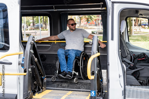 A man in a wheelchair on a lift of a vehicle for people with disabilities