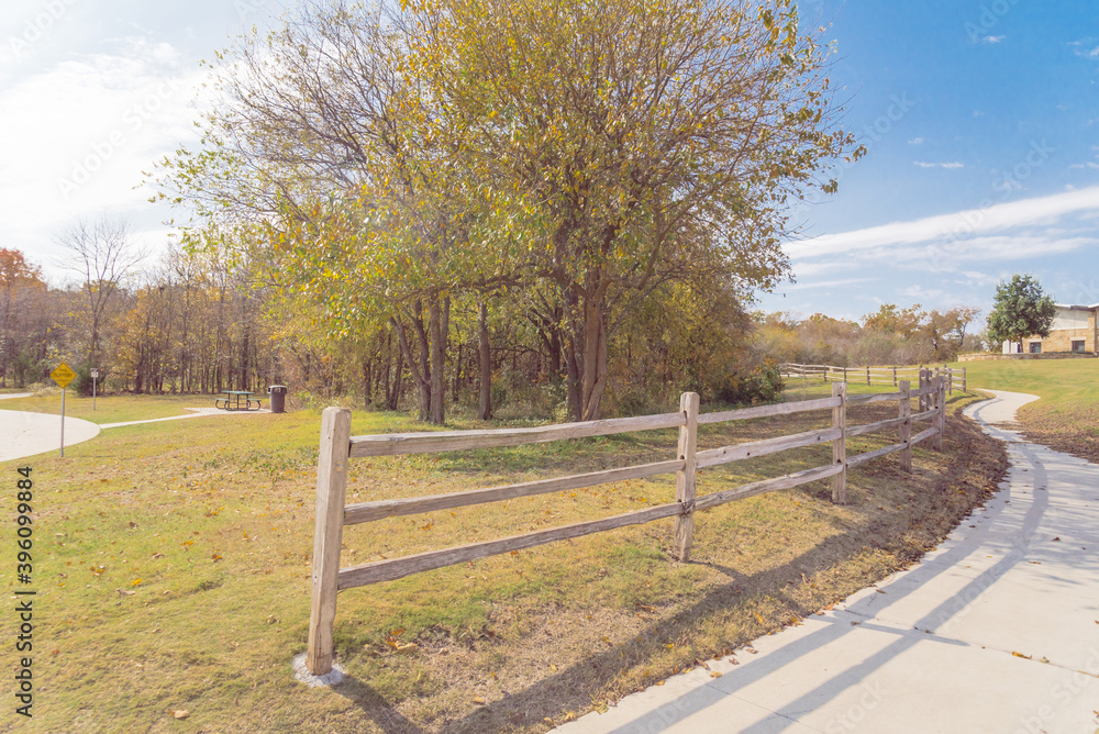 Long curved concrete pathway with rustic wooden fence and colorful fall foliage at park in Texas, USA Long curved concrete pathway with rustic wooden fence and colorful fall foliage at park in Texas, USA