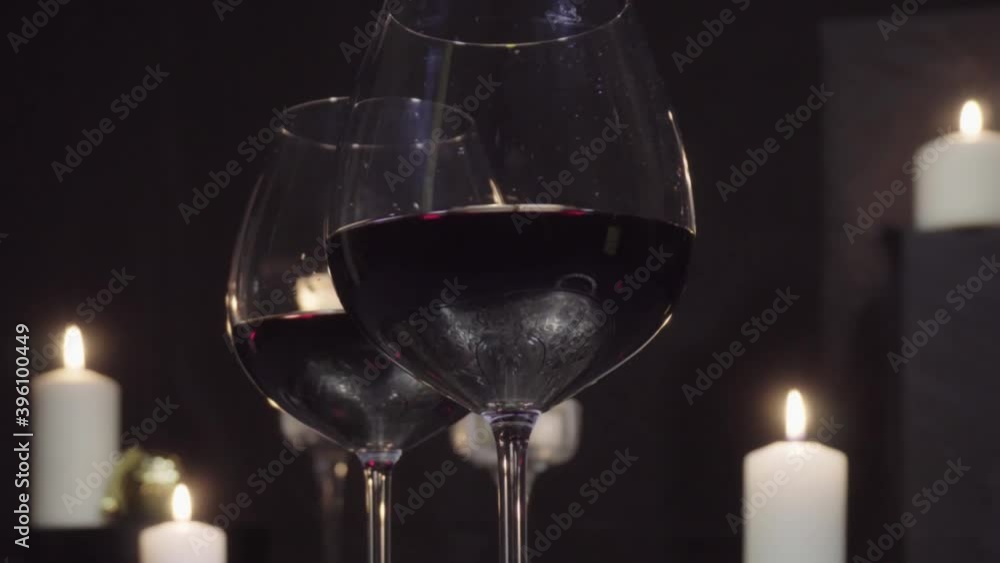 Glasses with red wine on the background of burning candles and Christmas and new year decorations Glasses with red wine on the background of burning candles and Christmas and new year decorations