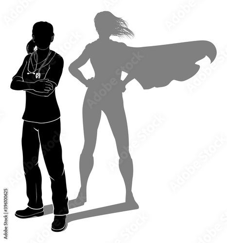 A doctor or nurse woman in silhouette wearing scrubs revealed as a super hero by her shadow.