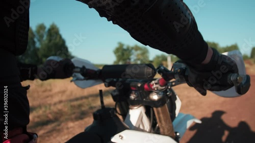 Close up tracking shot of unrecognizable man in full riding gear sitting on motorcycle and revving engine outdoors photo