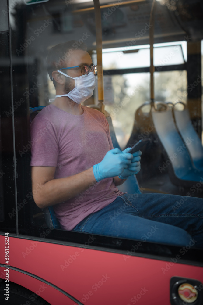 Man with medical protective mask and gloves sitting in an emtpy bus. Man with medical protective mask and gloves sitting in an emtpy bus.