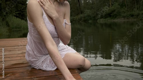 Sexy wet girl cools herself in the heat by washing her face and semi naked body with cold water from the lake