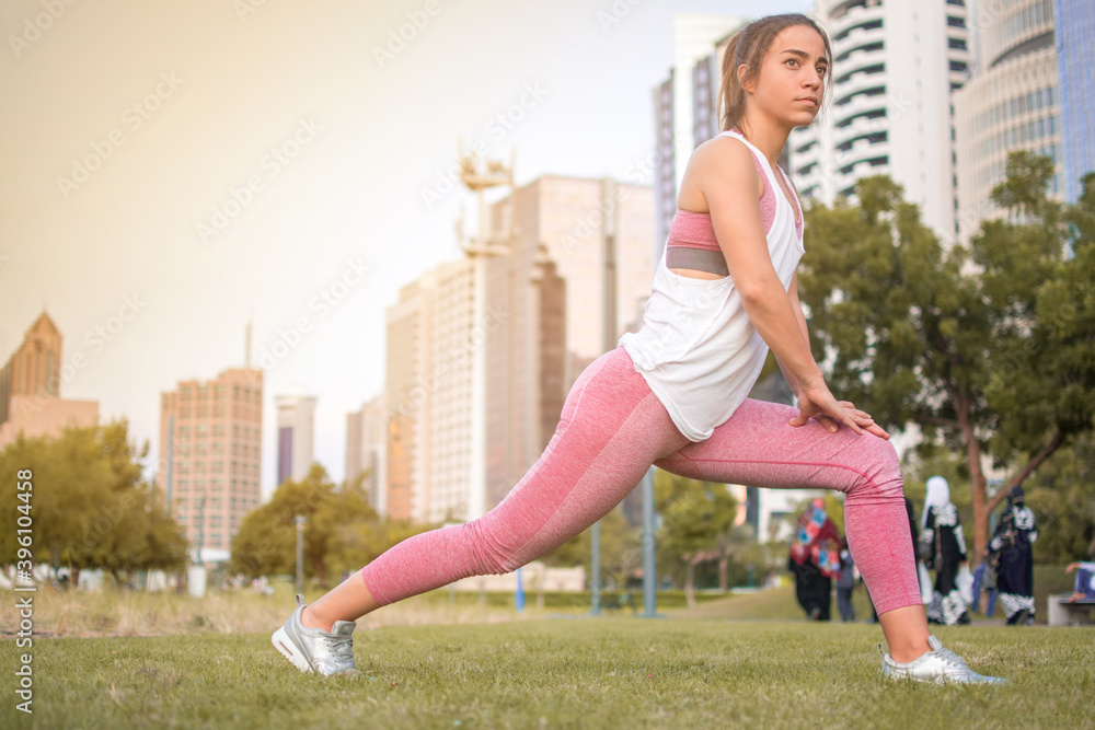 Exercise woman stretching leg muscles during outdoor running workout.