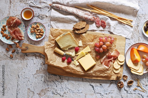 Appetizers table with various of cheese, curred meat, sausage, olives, nuts and fruits. Festive family or party snack concept. Overhead view.