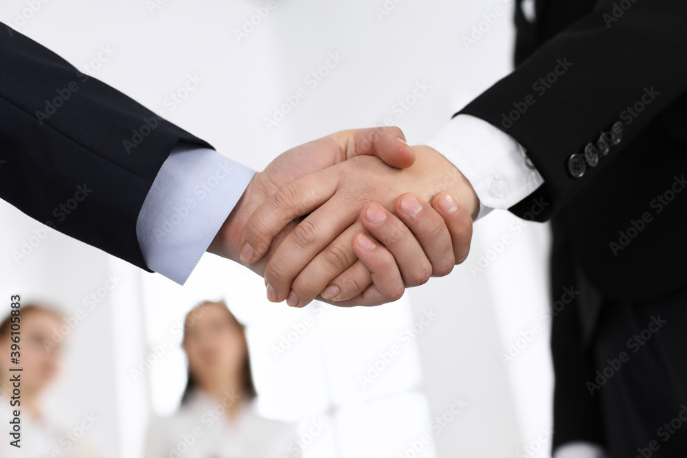 Businessman and woman shaking hands in office. Concept of handshake as success symbol in business