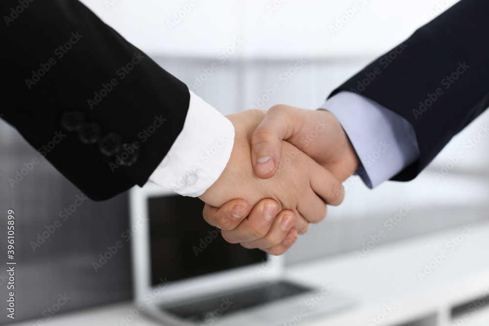 Businessman and woman shaking hands in office. Concept of handshake as success symbol in business Businessman and woman shaking hands in office. Concept of handshake as success symbol in business