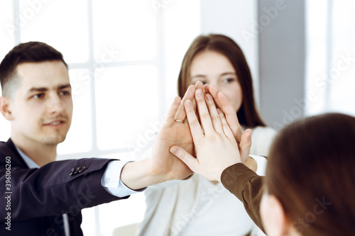 Business people group showing teamwork and joining hands or giving five in modern office. Unknown businessman and women making circle with their hands