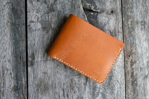 Tan brown leather bifold wallet on wood background