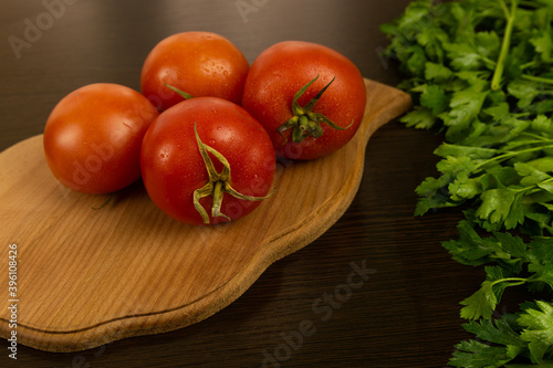 Red tomatoes on a wooden board and a dark textured wood background. With herbs.
Eco-friendly tomatoes. Fresh tomatoes. Tomatoes with water drops