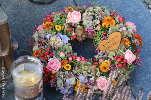 Am Friedhof im Herbst, Herbstdekoration einer Grabstätte in Form eines Blumenkranzes mit deutschsprachigem Schriftzug 