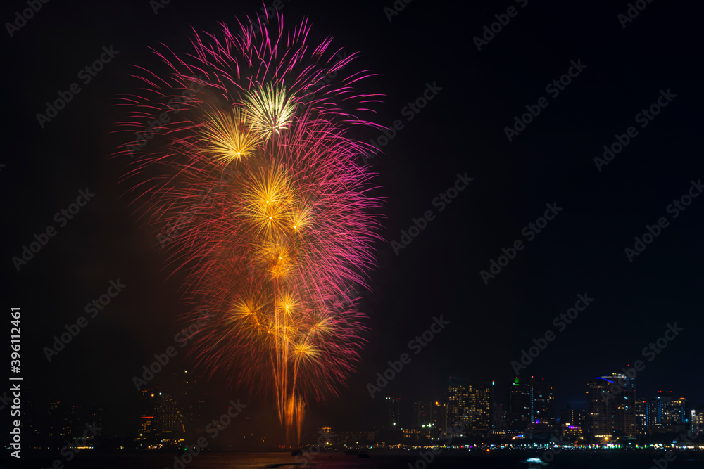 Firework festival with beach foreground and city background at Pattaya beach, Thailand. Colorful firework in celebration festival background