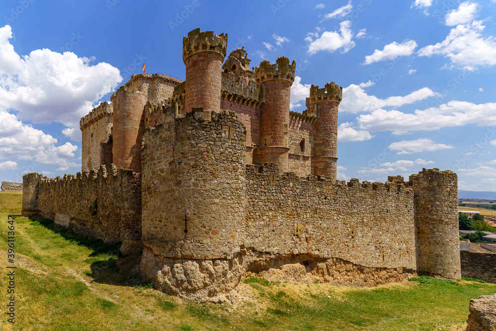 Castillo medieval en la provincia de Segovia con torres altas de piedra en día soleado con nuebes blancas. Turégano España.