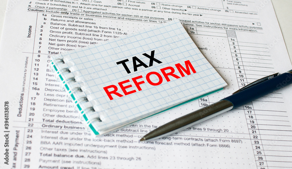 Notepad with text Tax Form lying on financial tables with a pen Notepad with text Tax Form lying on financial tables with a pen