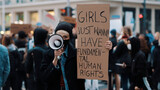 Girls just wanna have fundamental human rights. Woman march anti-abortion protest, woman holding banner and spaking into the megaphone. High quality photo