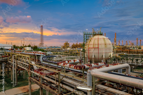 Gas storage tank and pipeline in oil refinery industrial plant at sunset