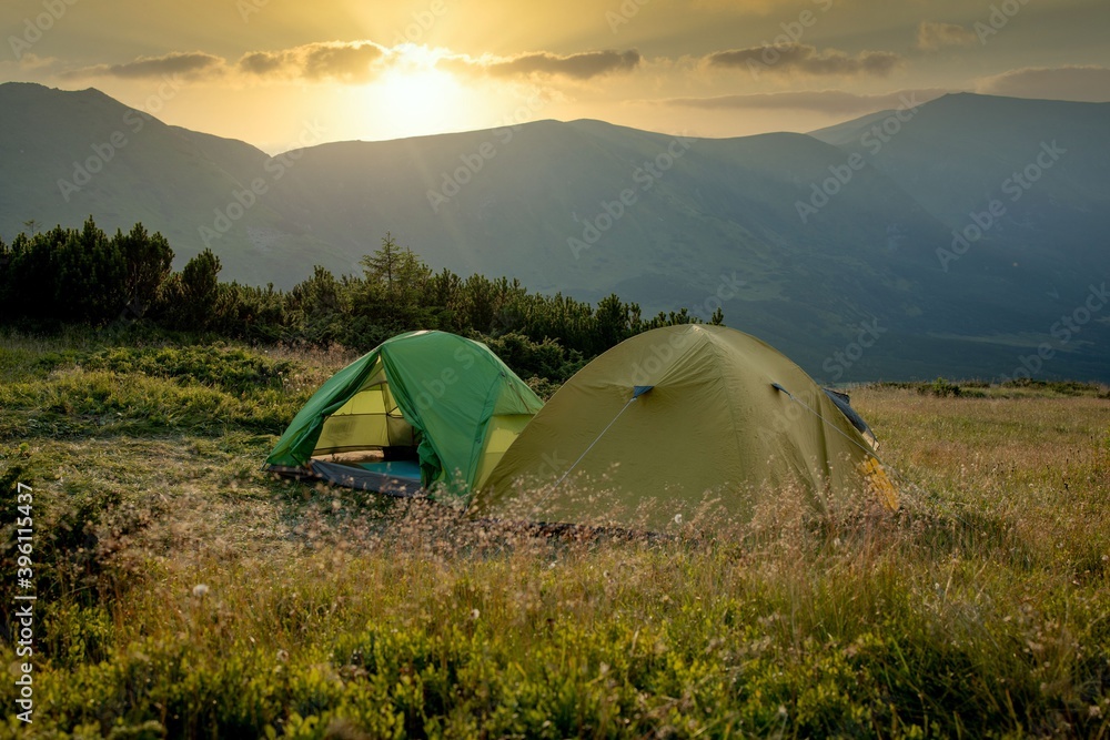 view of tourist tent in mountains at sunrise or sunset. Camping background. Adventure travel active lifestyle freedom concept. Summer vacation