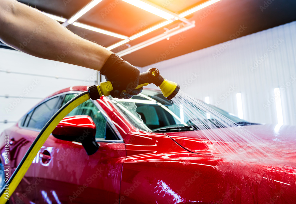 Naklejka premium Service worker washing car on a car wash.