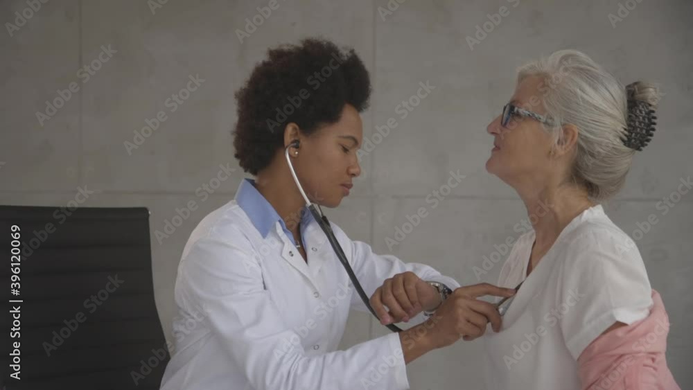 Senior woman with protective facial mask having a medical exam by black female doctor in the office Senior woman with protective facial mask having a medical exam by black female doctor in the office