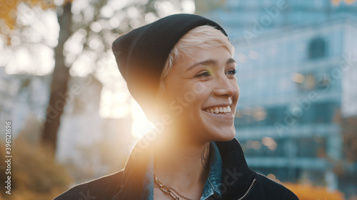 Portrait of young smiling woman with black hat and winter jacket in the city . High quality photo