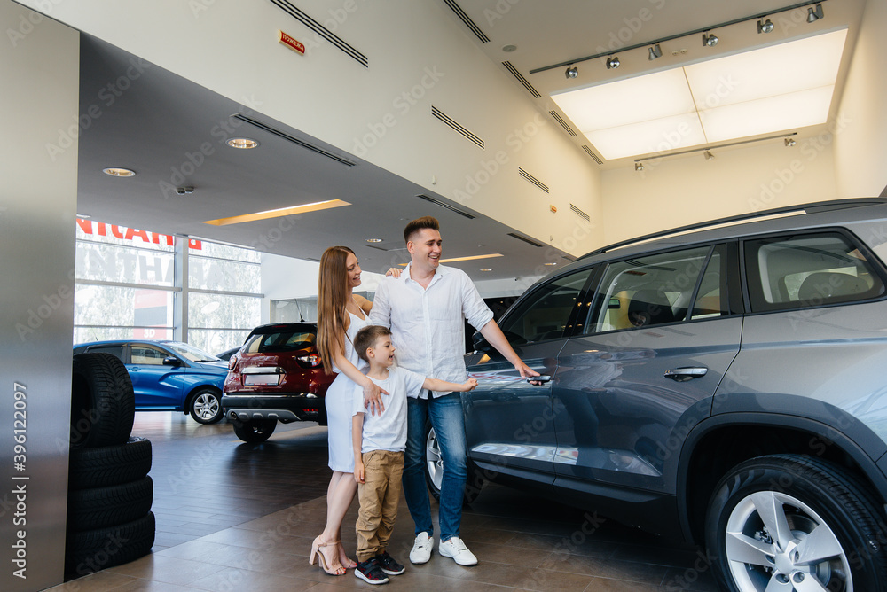 A happy young family chooses and buys a new car at a car dealership. Buying a new car A happy young family chooses and buys a new car at a car dealership. Buying a new car