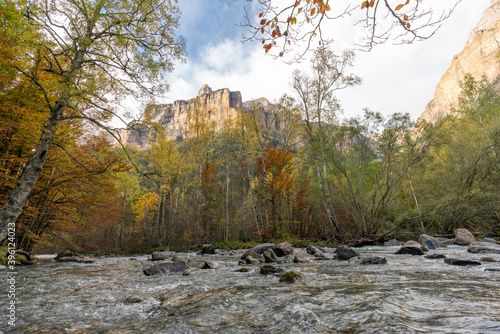 Running stream with many rocks through Autumn forest with Mountain Perdido  in Ordesa National park photo