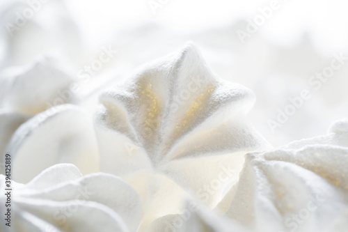 Blurred sweet crispy pink twisted meringue  zephyr  marshmallow made from egg whites  sugar and lemon on white food background. Selective focus  shallow depth of field.