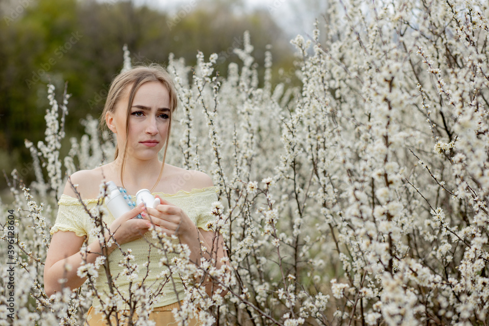 Woman with medicine in the hands Fighting Spring Allergies Outdoor - Portrait of an allergic woman surrounded by seasonal flowers Woman with medicine in the hands Fighting Spring Allergies Outdoor - Portrait of an allergic woman surrounded by seasonal flowers