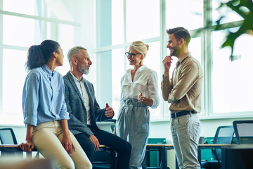 Group of successful multiracial people communicating and discussing business while standing in the modern office after meeting