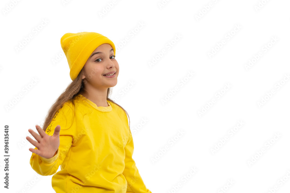 Young girl teeneger wearing yellow tracksuit and knitted hat gesticults with hands expressing joy, isolated Young girl teeneger wearing yellow tracksuit and knitted hat gesticults with hands expressing joy, isolated