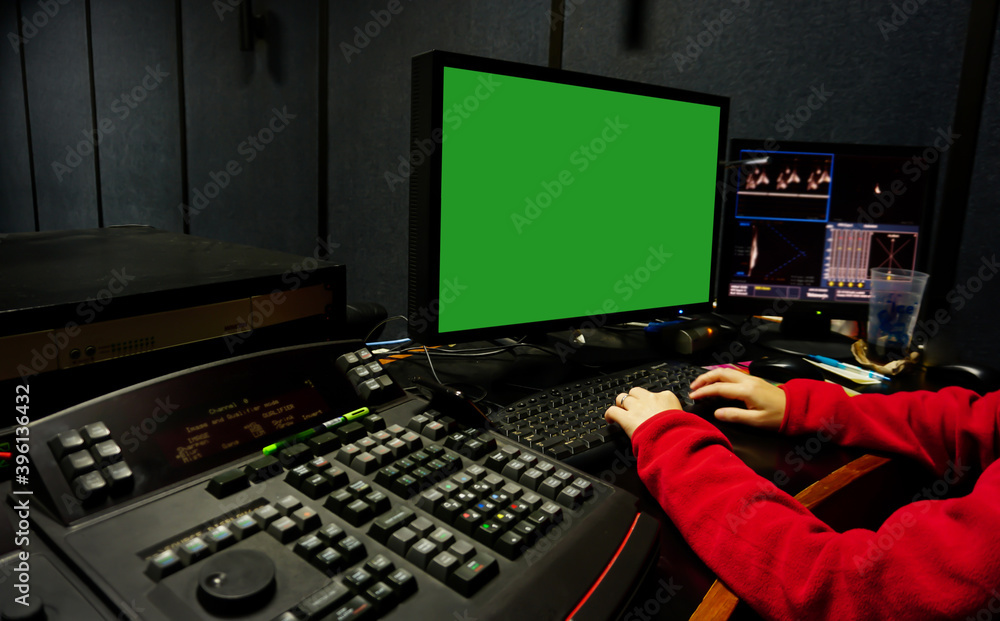 Fototapeta premium Men edit videos in a dark studio using modern color grading tools and equipment.Selective focus.Colour Grading. green screen. 
