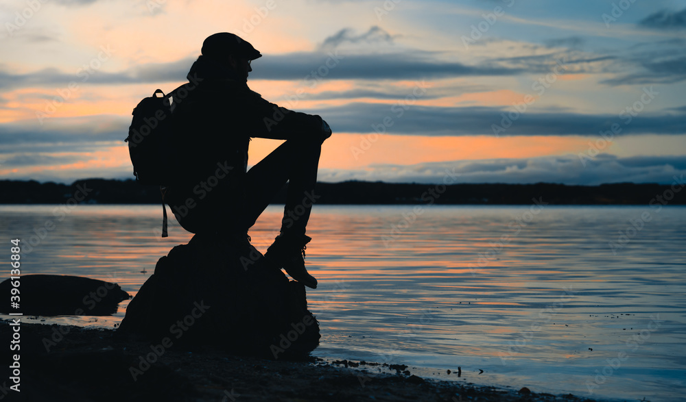 Silhouette of a man sitting on a rock at the sea