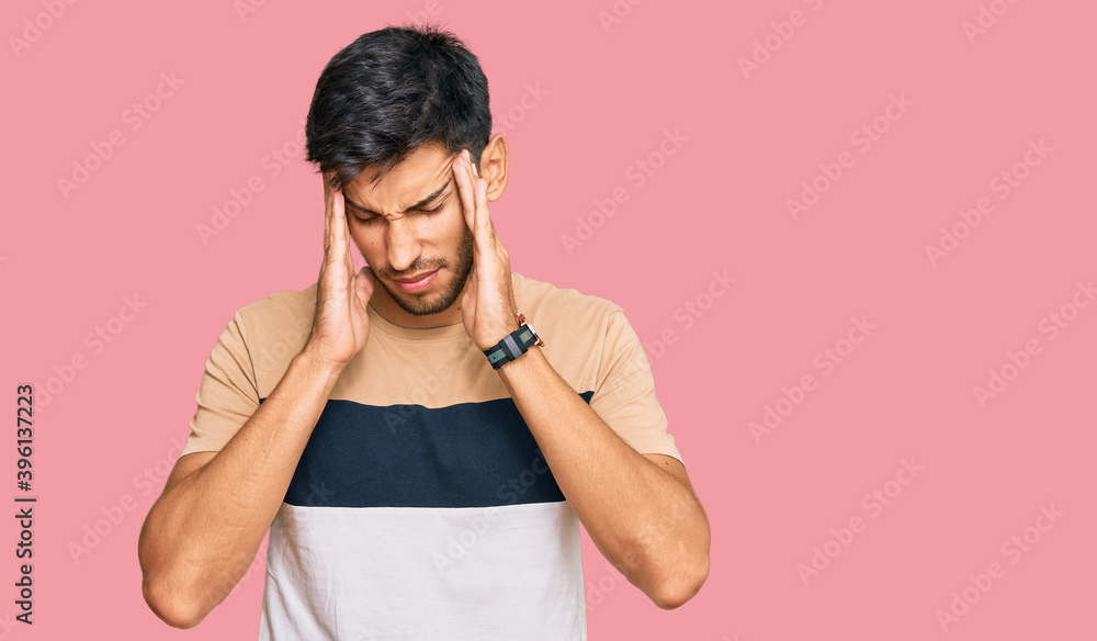 Young handsome man wearing casual clothes with hand on head, headache because stress. suffering migraine. Young handsome man wearing casual clothes with hand on head, headache because stress. suffering migraine.