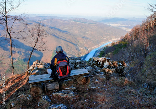 young man with a backpack from back sitting on a bench and looking at Drina river canyon, Serbia. Landscape, hike, tourism. Traveling alone