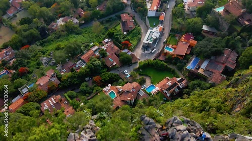 Aerial view over cliffs towards houses with pools, in Valle de Bravo town, in Mexico - tilt, drone shot photo