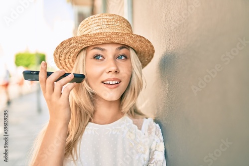 Young caucasian tourist girl listening audio message using smartphone at street of city. © Krakenimages.com