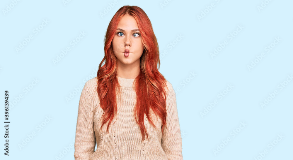 Young redhead woman wearing casual winter sweater making fish face with lips, crazy and comical gesture. funny expression. Young redhead woman wearing casual winter sweater making fish face with lips, crazy and comical gesture. funny expression.