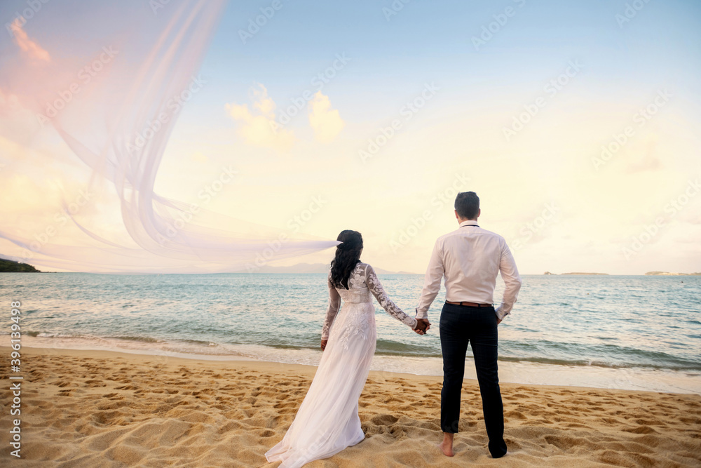The groom and not the bride stand on the beach of the sea and watch the sunset