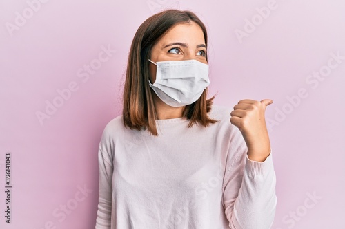 Young caucasian woman wearing medical mask smiling looking confident at the camera with crossed arms and hand on chin. thinking positive.