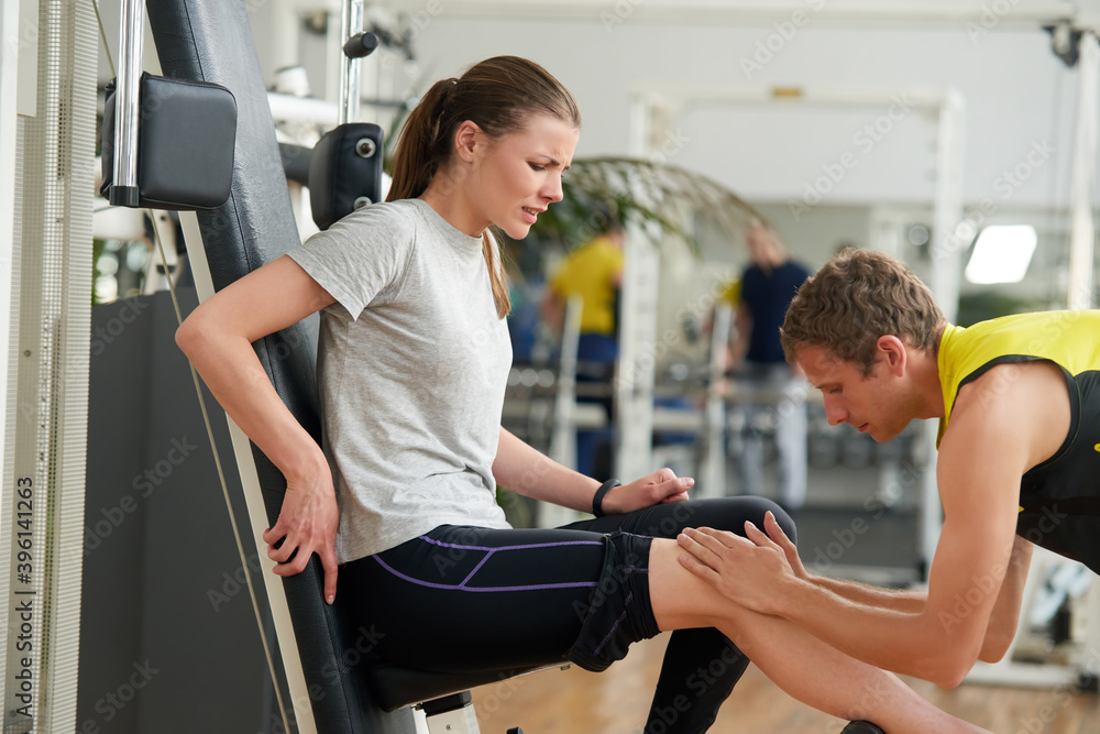 Young unhappy woman with leg injury at gym. Stressed girl suffering from severe knee pain after workout. Sport trauma concept. Young unhappy woman with leg injury at gym. Stressed girl suffering from severe knee pain after workout. Sport trauma concept.