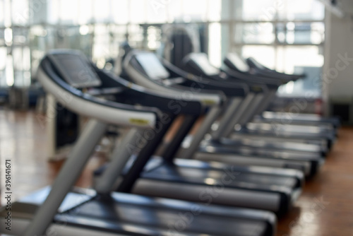 Abstract blur gym background. Blurred fitness center interior with treadmills. Blurred sport equipment at modern gym.