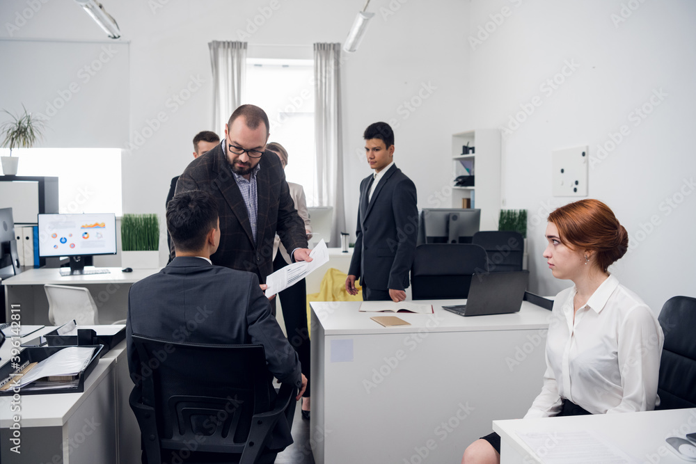 The supervisor inspects the work of Junior managers in the office of an Internet company. Spacious office for a large number of employees The supervisor inspects the work of Junior managers in the office of an Internet company. Spacious office for a large number of employees